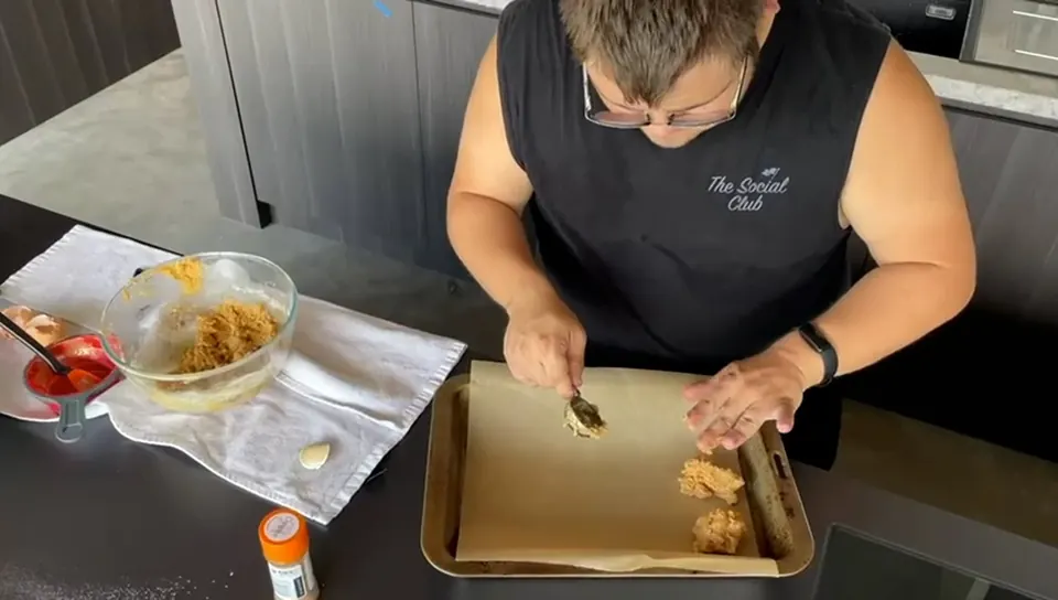 A participant shaping patties on a baking tray during a cook-along.