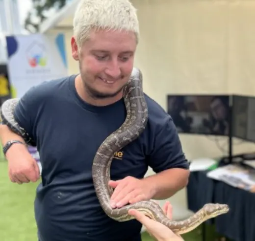 Dan smiling with a python draped over his shoulders.