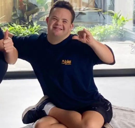 Ethan sitting cross-legged giving two thumbs up.