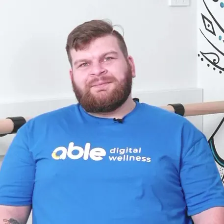 Kane in a blue Able t-shirt, smiling.